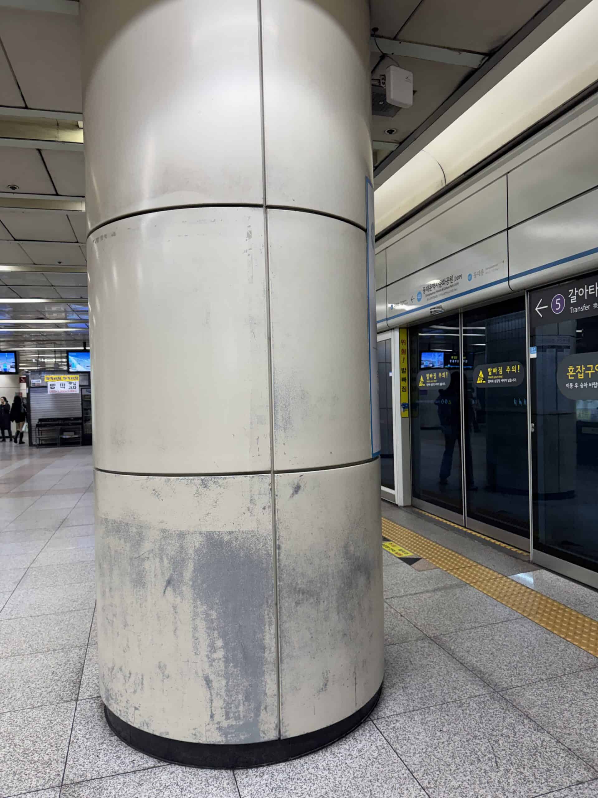 捷運月台圓柱金屬包板底部因行李箱與清潔設備碰撞導致烤漆剝落與金屬基材外露